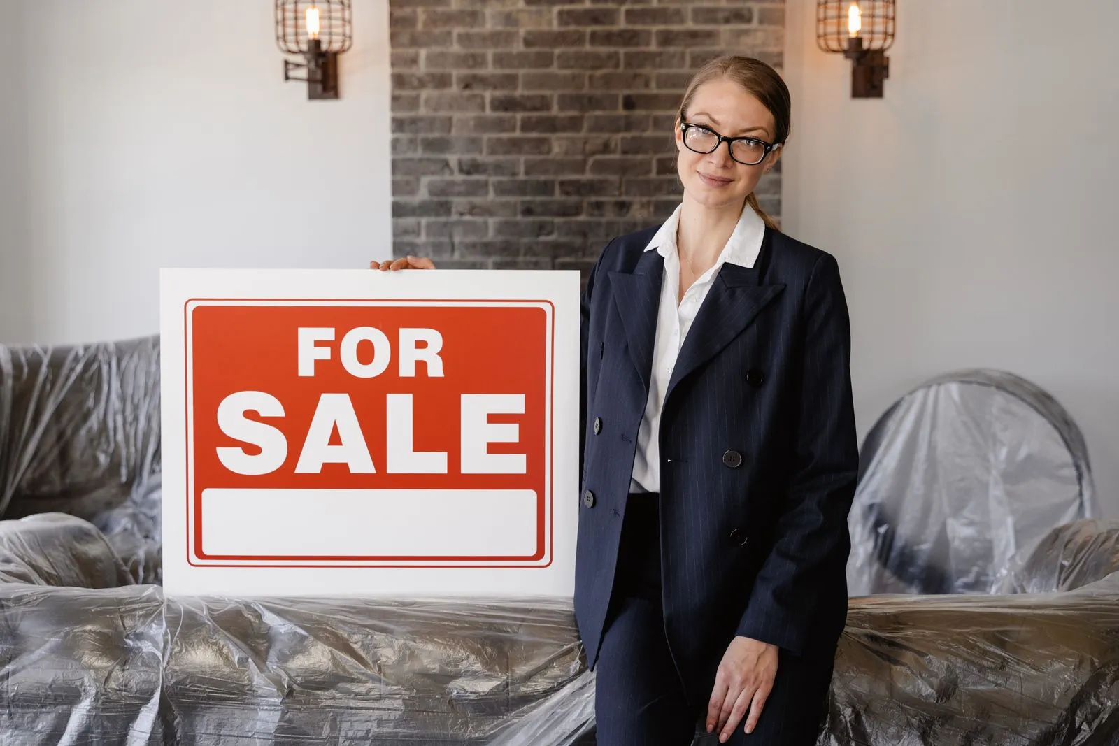 Agente immobilière à côté d'un panneau de vente dans un logement en travaux
